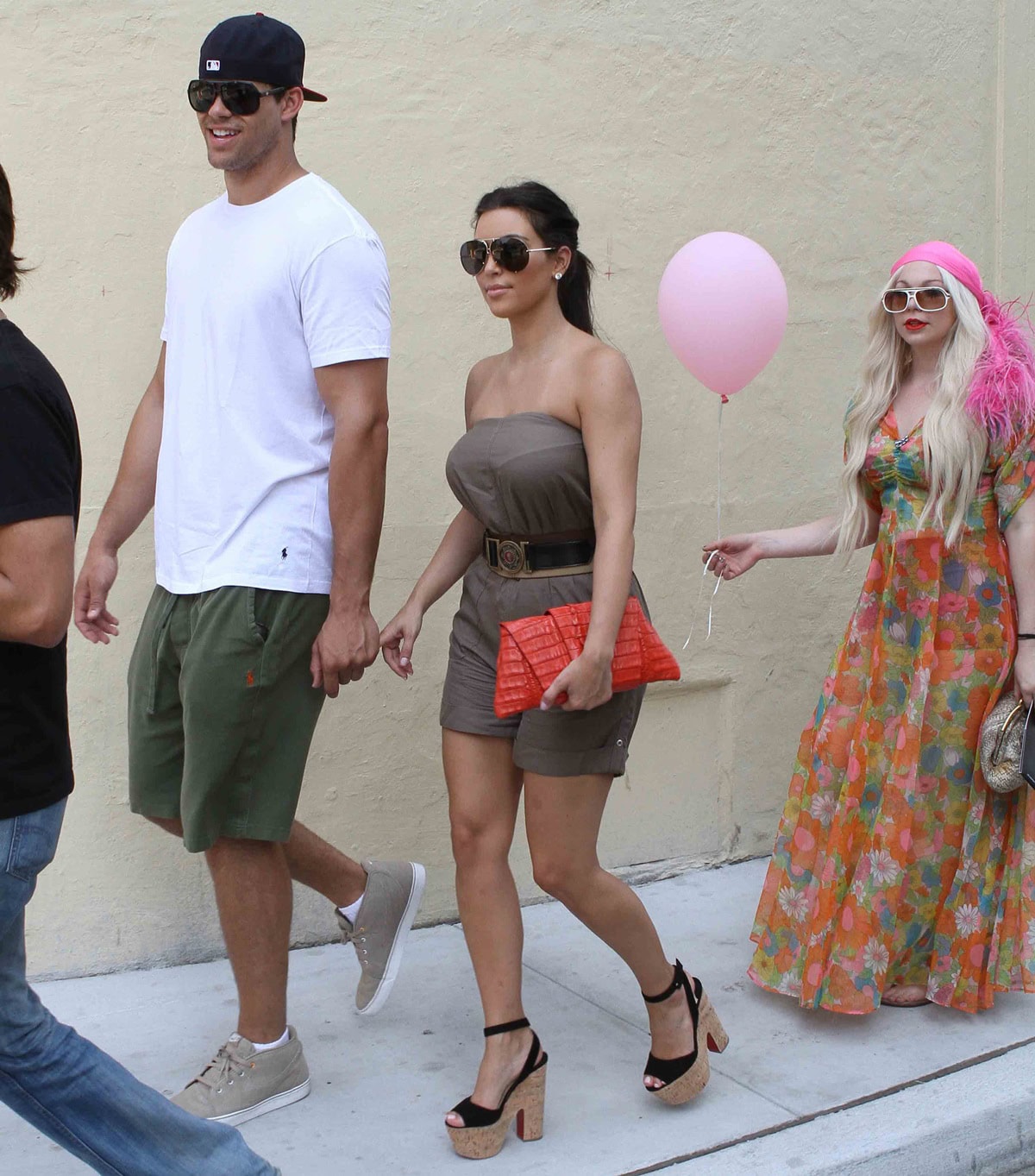 Kim Kardashian pairs her Christian Louboutin cork platform sandals with a khaki romper and vibrant orange clutch during a Miami outing with Kris Humphries