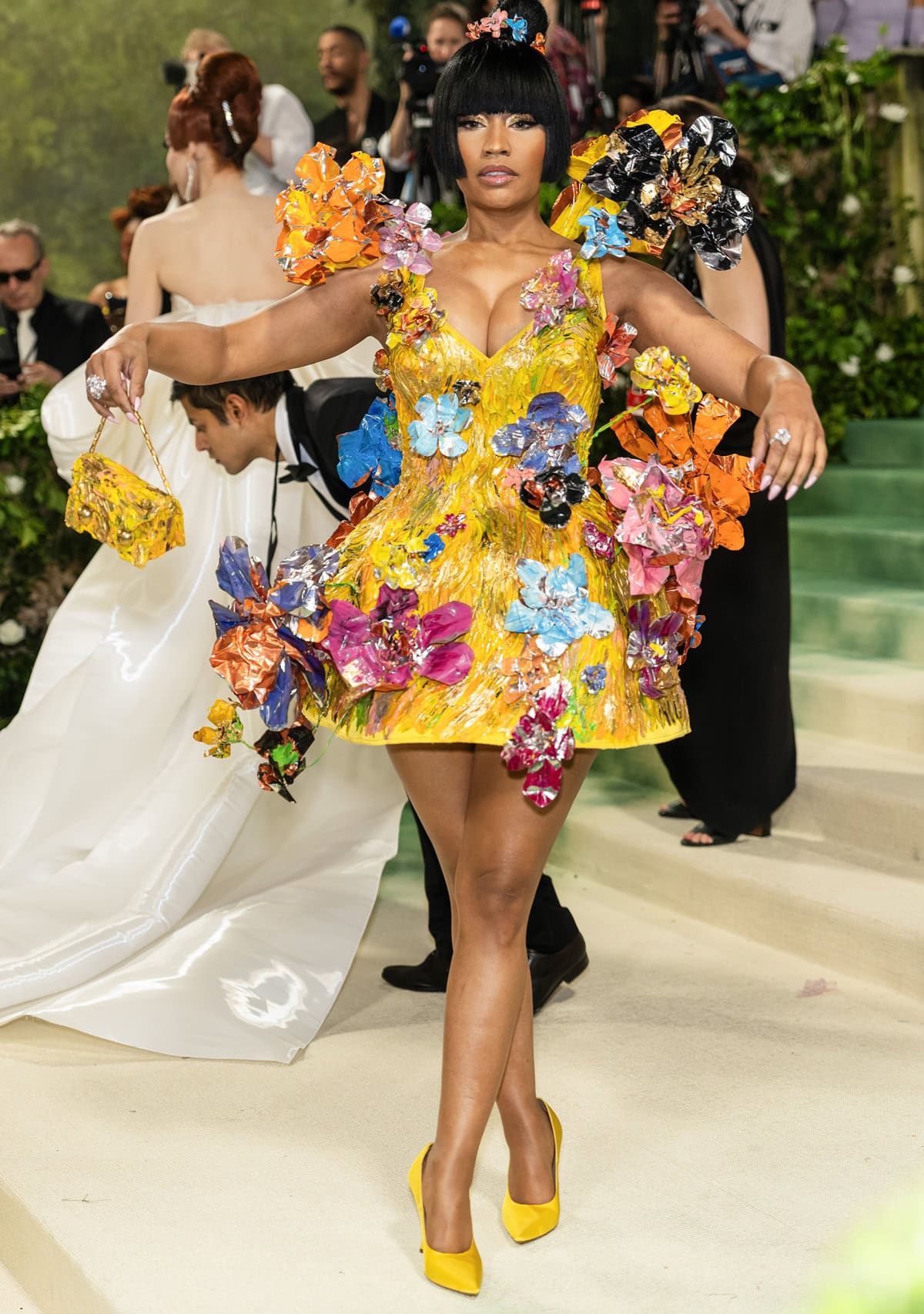 Global icon Nicki Minaj stuns in a custom Marni sculptural hourglass dress crafted from yellow silk duchesse and adorned with hand-painted aluminum flowers, perfectly complemented by matching satin pumps and a one-of-a-kind Trunkaroo bag at the 2024 Met Gala on May 6, 2024, at the Metropolitan Museum of Art in New York City