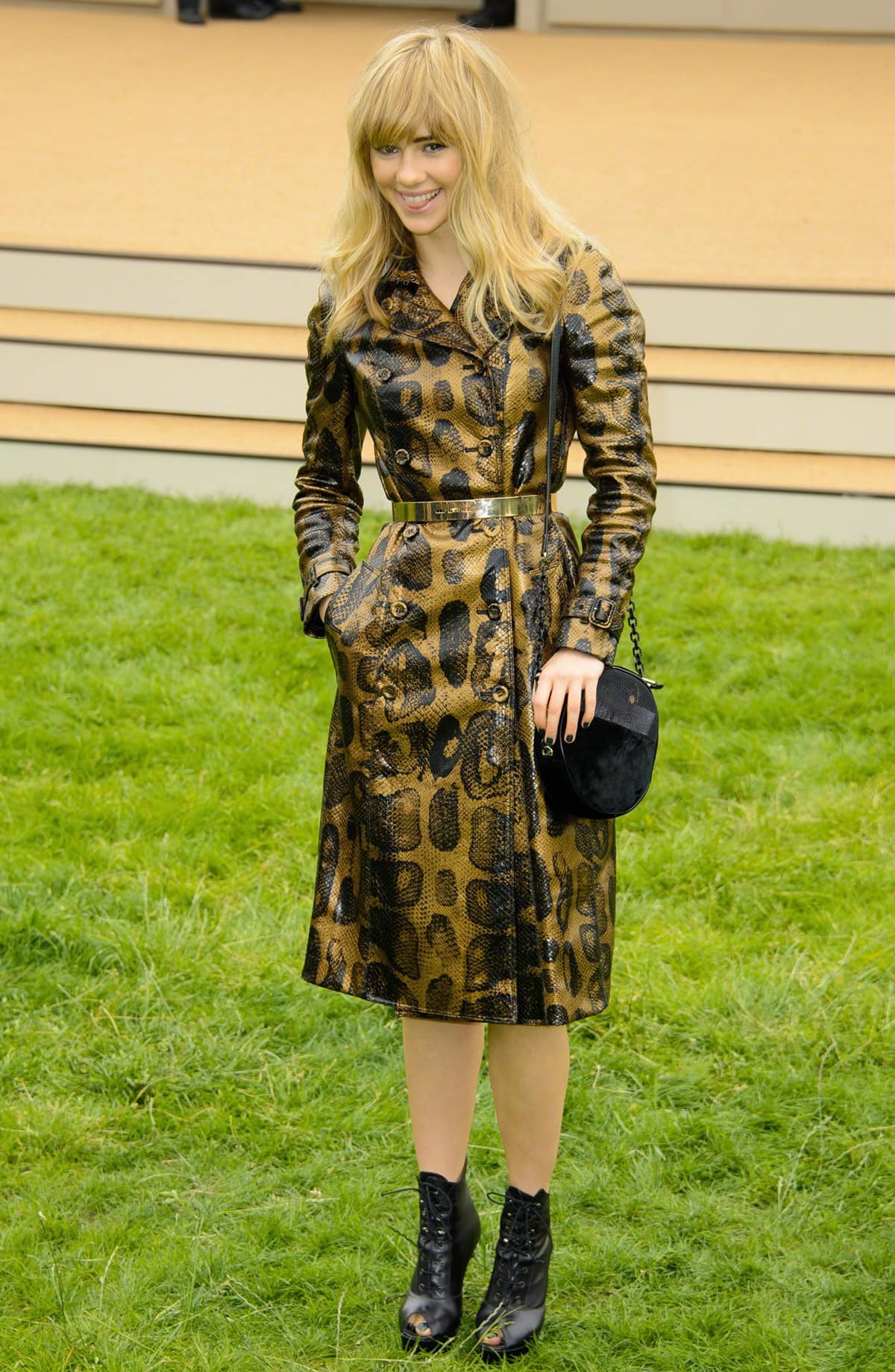 Suki Waterhouse epitomized glamour at the Burberry Prorsum SS14 show, where she sported a bronze and black snakeskin trench coat, stylishly cinched at the waist with a metallic belt