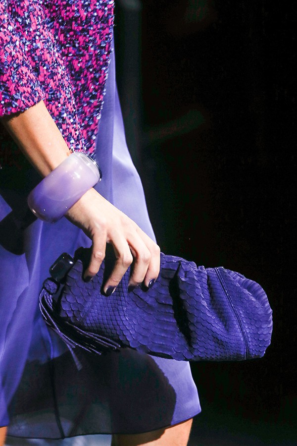 Model holding a luxurious textured purple Giorgio Armani clutch, complemented by a stylish purple bangle