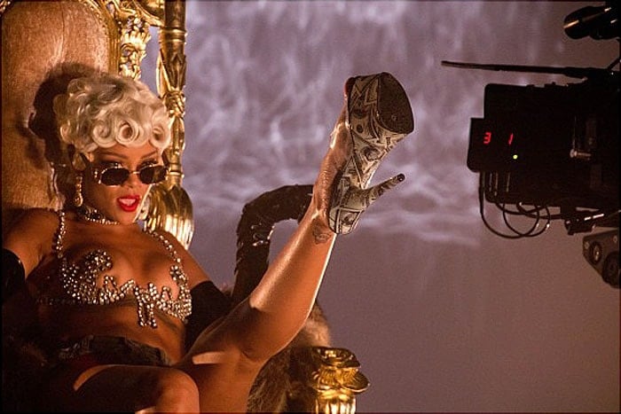 Rihanna showing her dollar-printed stripper heels to the camera while shooting her "Pour It Up" music video