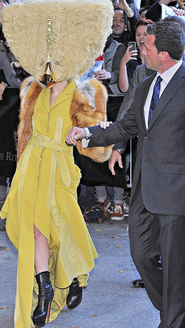 Lady Gaga holds on to her bodyguard while leaving the Ritz Carlton hotel in Berlin, Germany, wearing a dramatic yellow dress and lace-up platform boots on October 24, 2013