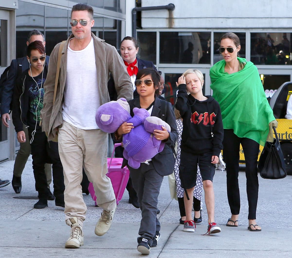 Angelina Jolie adds a pop of color with a bright green wrap while walking through LAX with Brad Pitt and their children