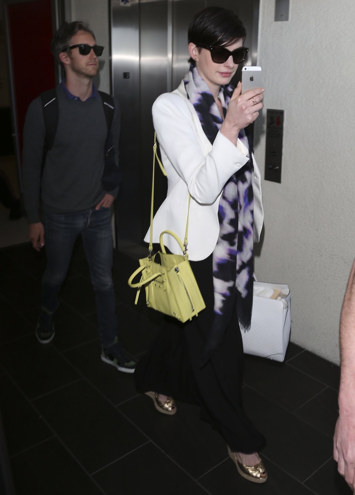Anne Hathaway has some fun with her iPhone camera while arriving at LAX Airport on March 10, 2014, with her husband Adam Shulman following a few paces behind