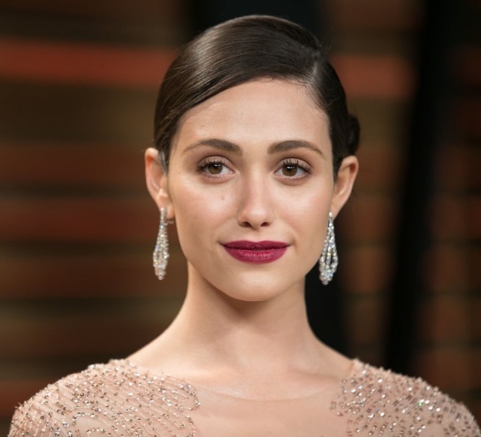 Emmy Rossum's hair was styled in a chic updo to show off her stunning statement earrings and dramatic red lips