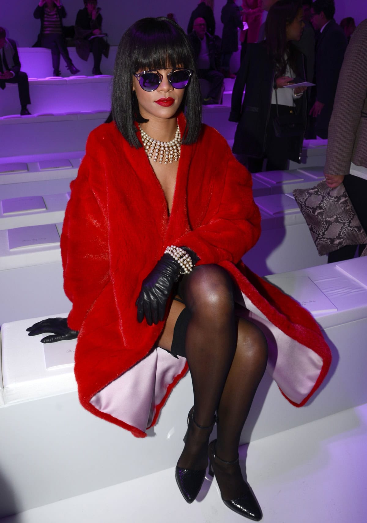 Rihanna attended the Christian Dior show in Paris on February 28, 2014, wearing Dior So Real sunglasses, a Dior Pre-Fall 2014 outfit, Wolford Individual 10 stockings, Dior Fall 2014 sandals, and a Dior Pre-Fall 2013 necklace