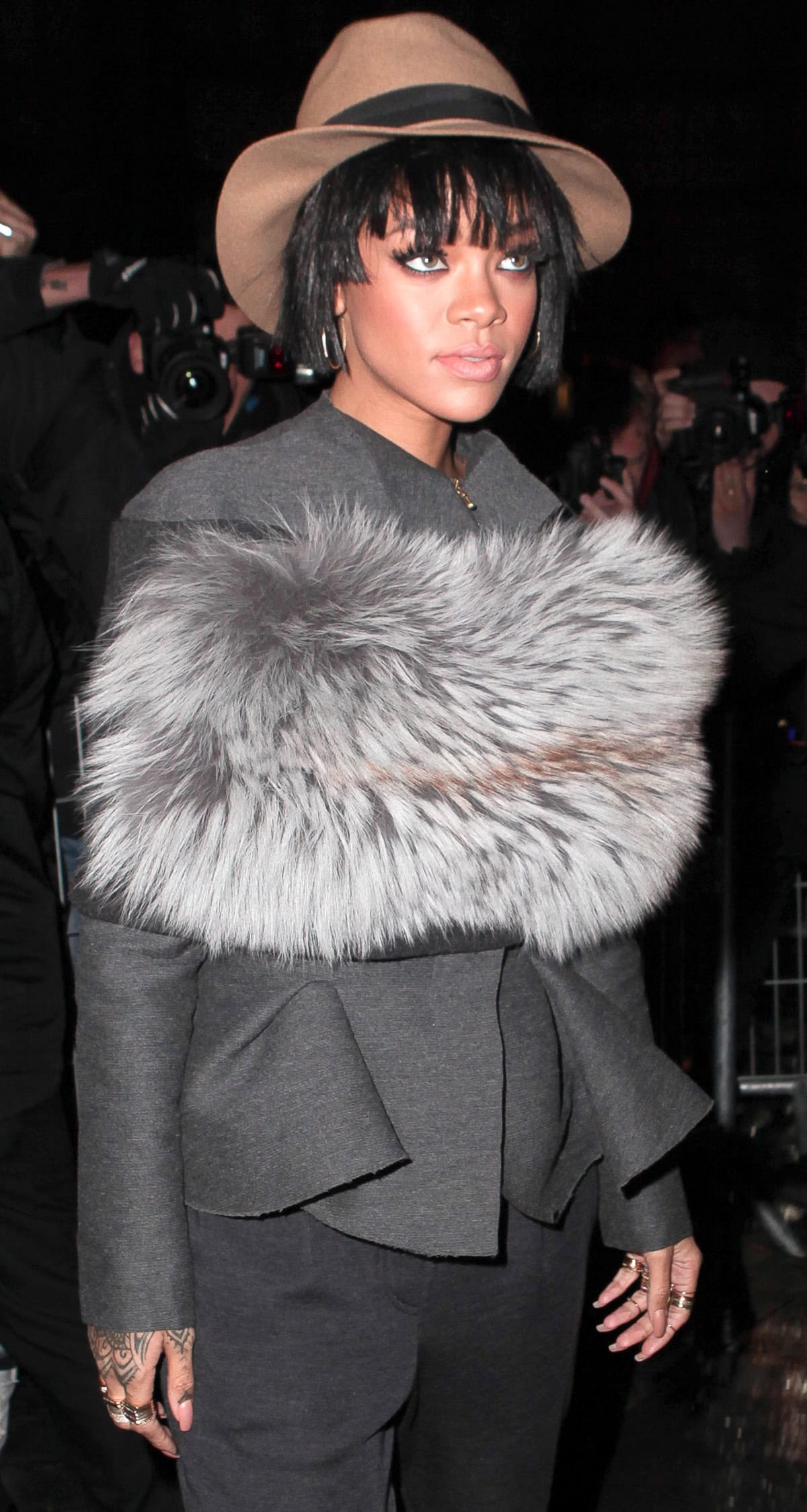 Rihanna rocks a chic gray ensemble with a statement fur stole and a stylish hat at the Lanvin show during Paris Fashion Week 2014