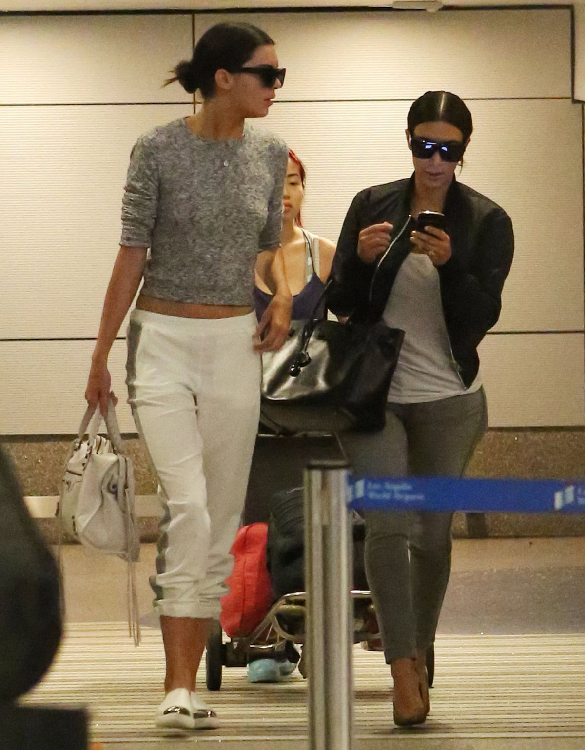 Kendall Jenner at LAX Airport on July 10, 2014, wearing a Topshop space dye knit sweater, rib side stripe joggers, Miu Miu metal cap-toe sneakers, and a Balenciaga Arena Classic City bag in Bianco