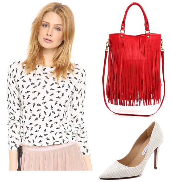 Model showcasing a chic outfit: a printed bunny sweater, paired with a stylish red fringe handbag and elegant white stiletto pumps