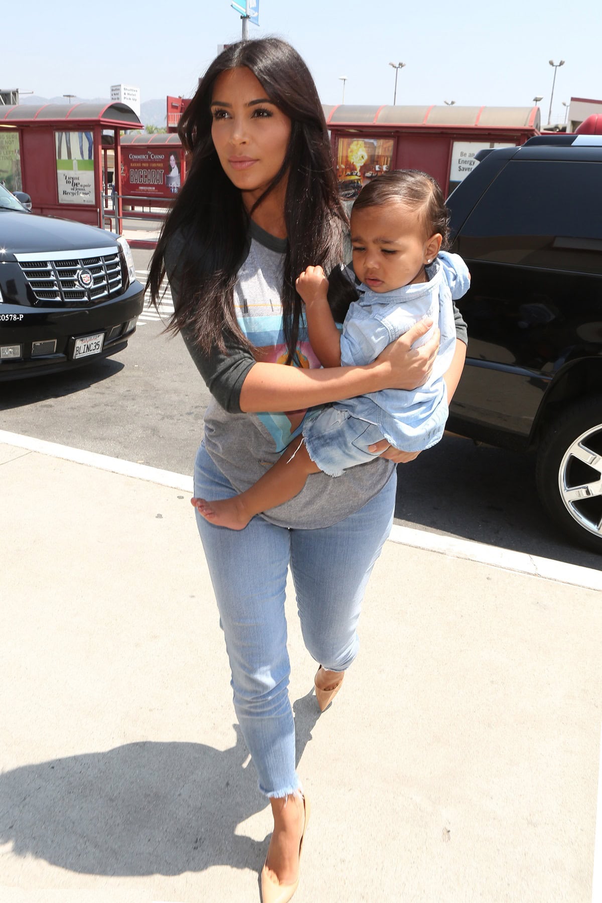 Kim Kardashian and her daughter North West coordinate in stylish denim outfits, with Kim in light blue jeans and a graphic tee while North wears a cute denim shirt and matching shorts