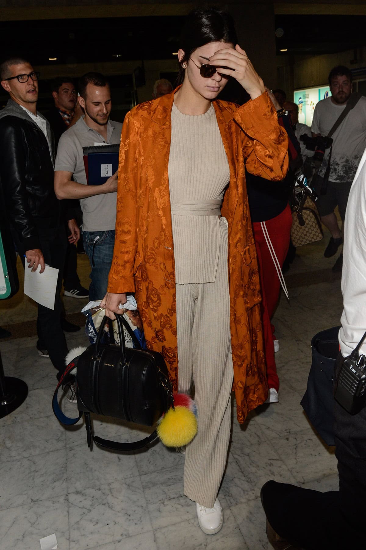 Kendall Jenner at Nice Airport in Cannes, France, on May 11, 2016, wearing an Elle Sasson Anouck belted sweater in sand, Elle Sasson Bardot sweater pants, and accessorizing with a Fendi Smile fur pom-pom charm