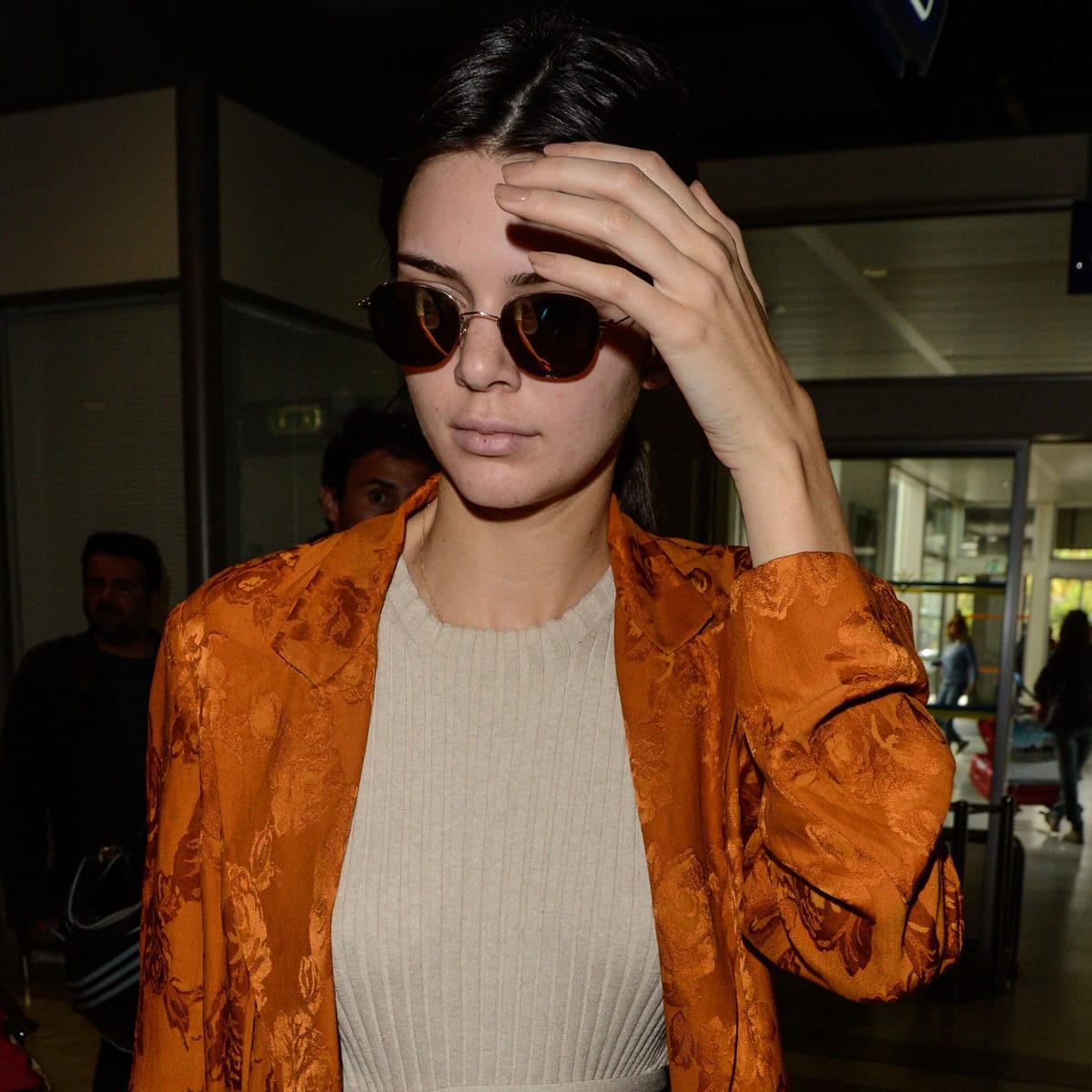 Kendall Jenner shields her face with sunglasses, showing a natural look with visible acne