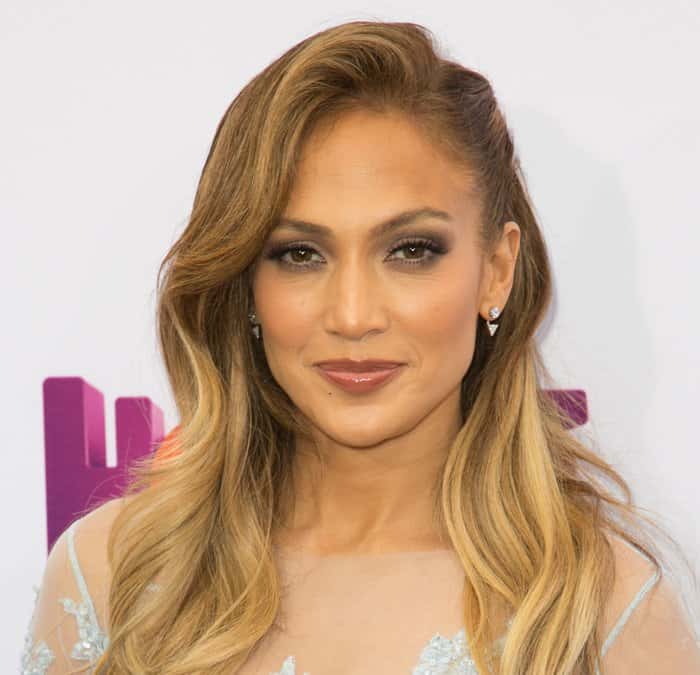 Jennifer Lopez styled her delicate light blue Zuhair Murad lace dress with soft, wavy golden locks, subtle smoky eye makeup, nude glossy lips, and elegant diamond stud earrings