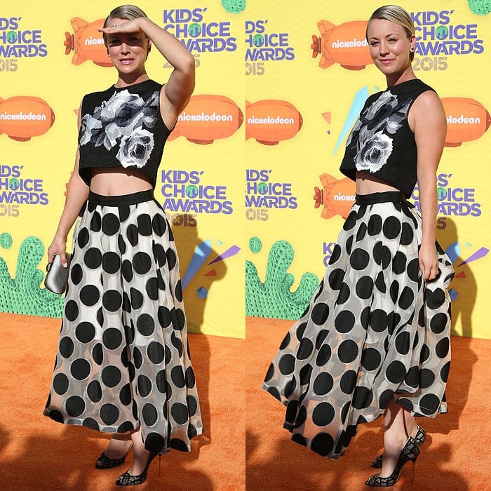 Kaley Cuoco fighting the glare of the sun while posing on the orange carpet