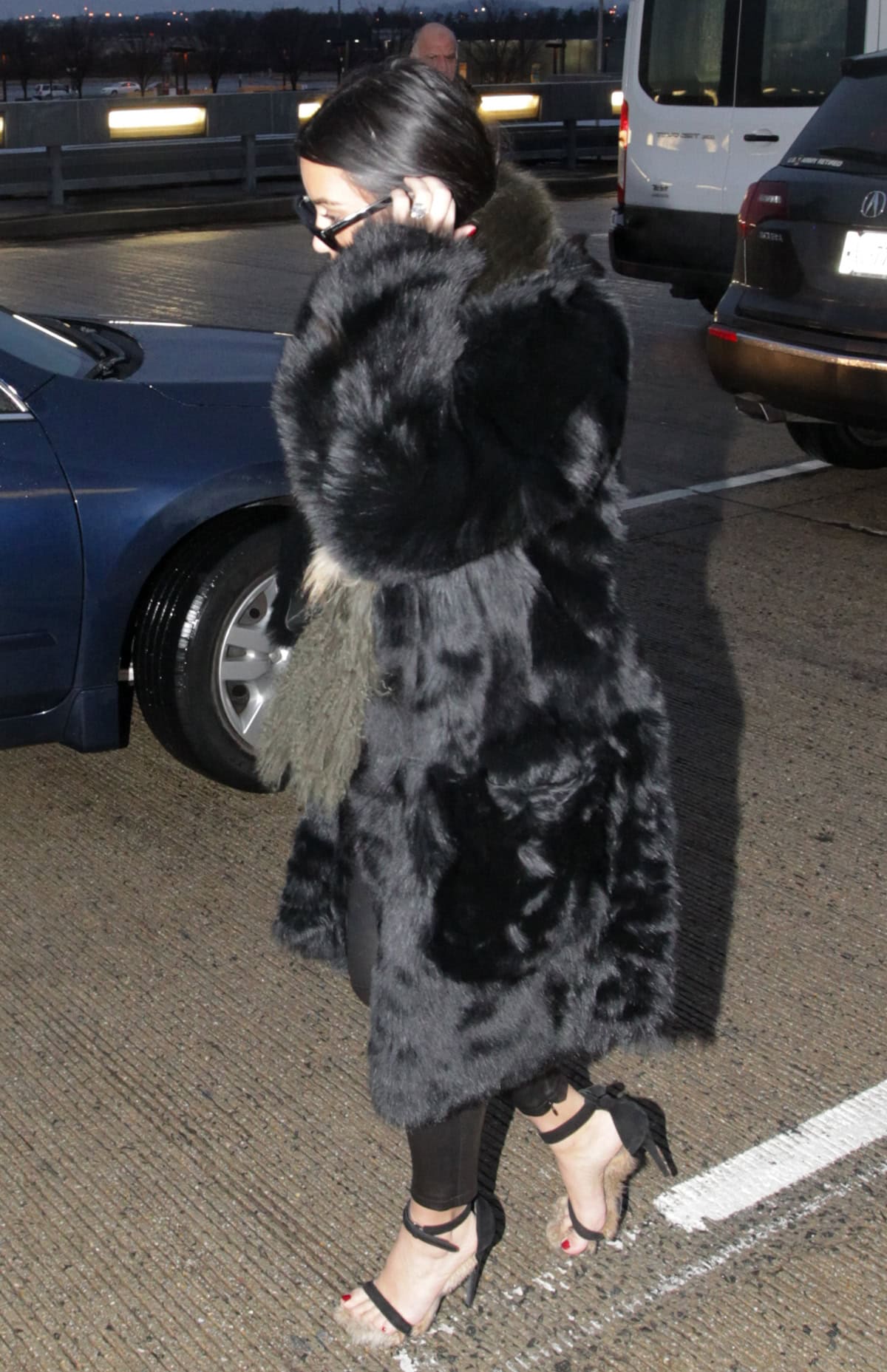 Kim Kardashian wore a black fur coat over black leather pants and strappy black sandals that displayed her dark toe polish in the arrivals hall at Washington Dulles International Airport