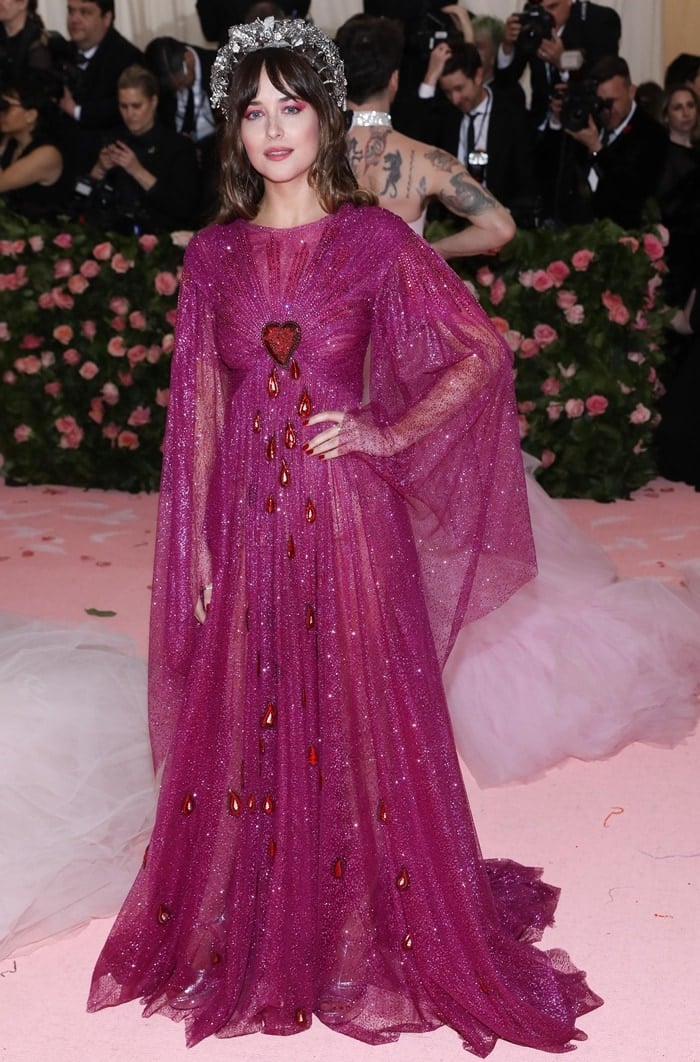 Dakota Johnson dazzles in a shimmering magenta Gucci gown featuring a Sacred Heart detail, paired with a striking silver headpiece