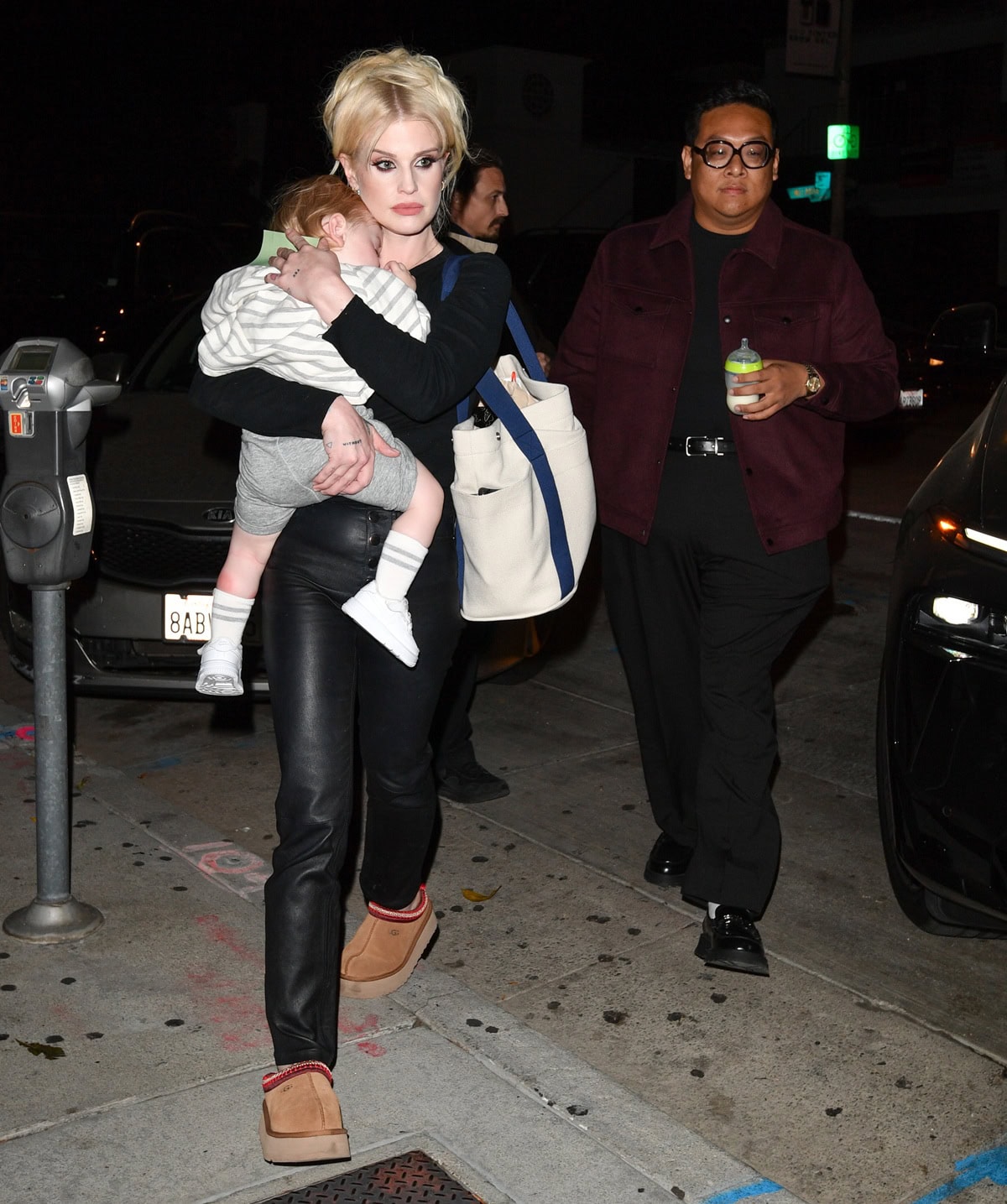 Kelly Osbourne carries her son Sidney Osborne Wilson while stepping out in black leather pants, a fitted sweater, and cozy platform UGG Tazz slippers at Craig's restaurant for best friend Daniel Nguyen's birthday celebration