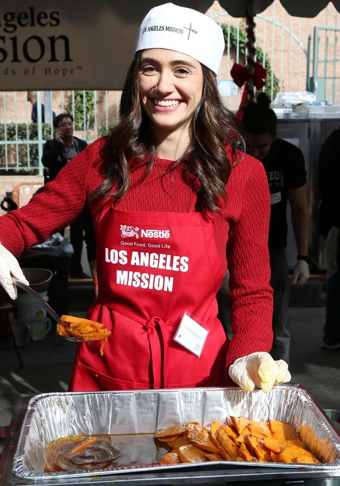 Emmy Rossum wears a "Los Angeles Mission" paper hat over her hair as she helps feed the homeless on Christmas Eve in Los Angeles