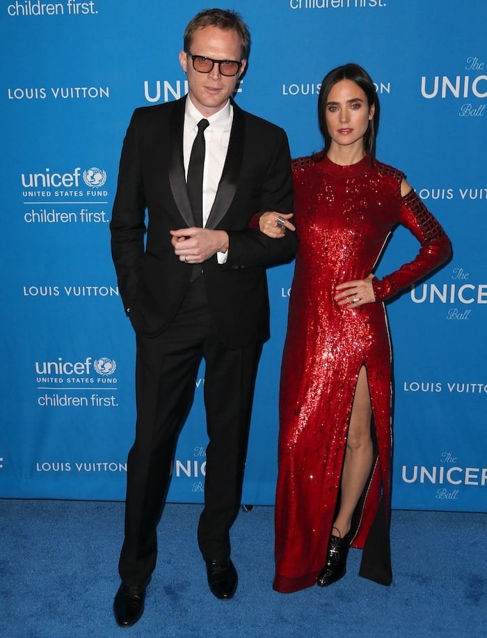 Jennifer Connelly stuns in a red sequined Louis Vuitton gown with a thigh-high slit, accompanied by her husband Paul Bettany at the 6th Biennial UNICEF Ball