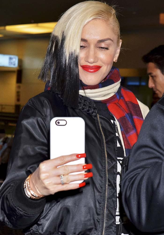 Gwen Stefani spends some time on her phone at the Tokyo airport