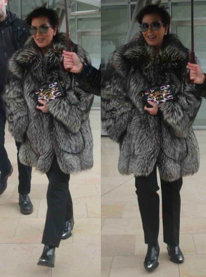 Kris Jenner hides from the Paris weather on her way to the Luis Vuitton show during Paris Fashion Week on March 9, 2016