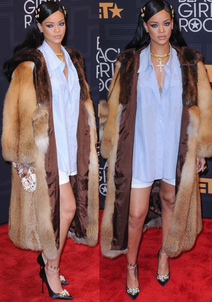 Rihanna rocks the red carpet in an oversized fur coat, blue button-up shirt, white shorts, and pearl-embellished satin pumps at the BET Black Girls Rock! Awards