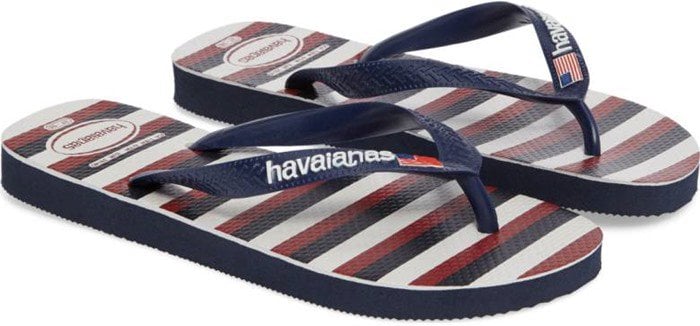 A small American flag graces the toe strap of a comfortable rubber flip-flop styled with a bold flag motif on the footbed