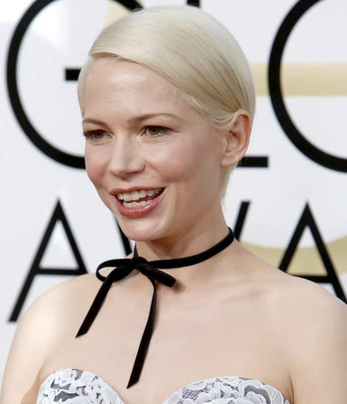 Michelle Williams complements her sleek platinum blonde hairstyle with a delicate black ribbon choker