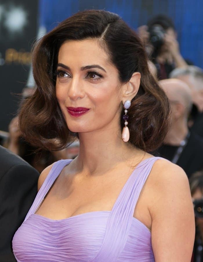 Amal Clooney stuns with her vintage-inspired waves, deep berry lips, and exquisite Lorraine Schwartz earrings featuring a mix of jade, coral, sapphire, and diamonds