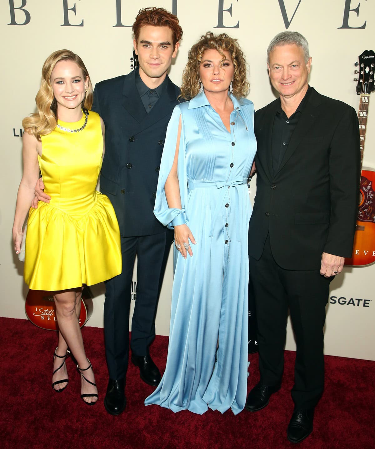 Britt Robertson looks noticeably petite in a bright yellow Christopher Kane Fall 2019 mini dress with voluminous skirts, standing beside KJ Apa, Shania Twain, and Gary Sinise at the I Still Believe premiere