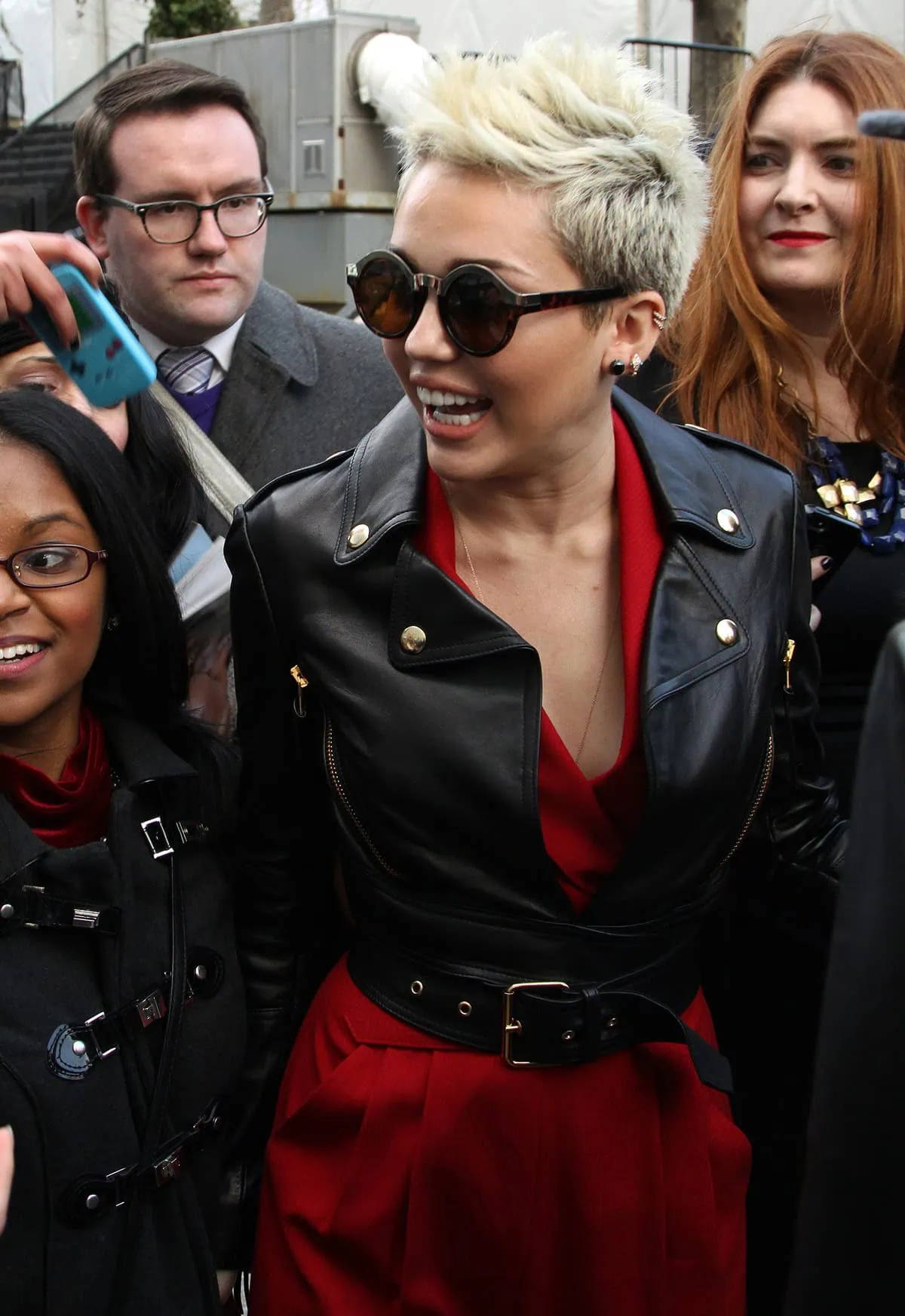 Miley Cyrus rocks a bold look in a red belted jumpsuit paired with a chic black leather jacket
