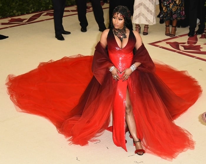 Nicki Minaj in a custom Oscar de la Renta red gown, tulle coat, rosary headpiece, and Le Silla 'Gaga' fur sandals.