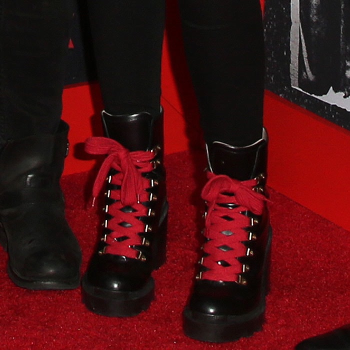 Paris Jackson adds a bold statement to her rock-inspired outfit with black hiker boots featuring thick lug soles, chunky block heels, and eye-catching red laces