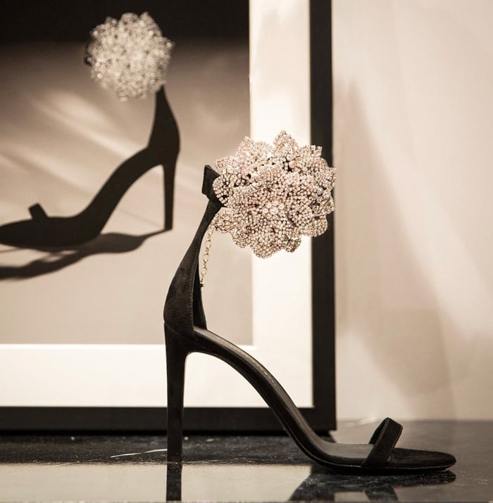 These high-heel, black suede sandals are characterized by the crystal flower accessory on the side