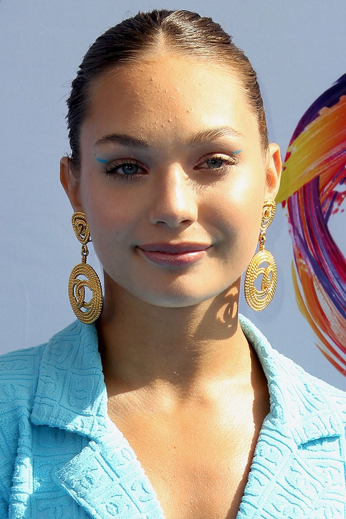 Maddie Ziegler wearing gold Chanel logo disc earrings and blue eyeliner streaks