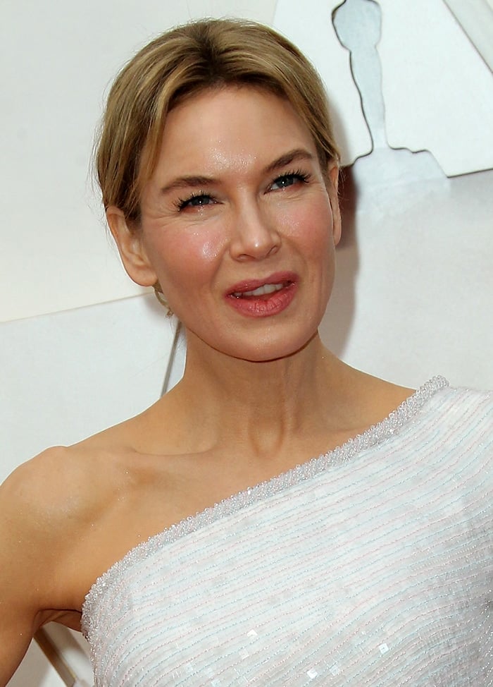 Renee Zellweger wears a chic center-parted updo and her signature soft pink makeup-look 