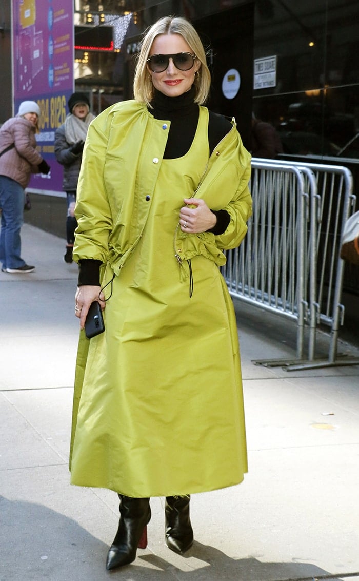 Kristen Bell steps out in New York City wearing a bold lime-green dress, paired with a matching jacket, black turtleneck, and sleek black boots, showcasing her chic street style