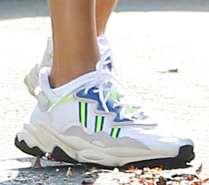 Hailey Bieber completes her look with Adidas Ozweego sneakers in solar yellow and blue colorway