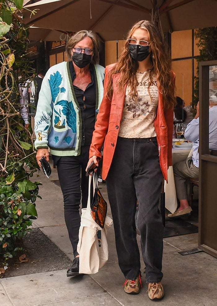 Bella Hadid tops her look with red leather jacket, tinted sunglasses, and black face mask