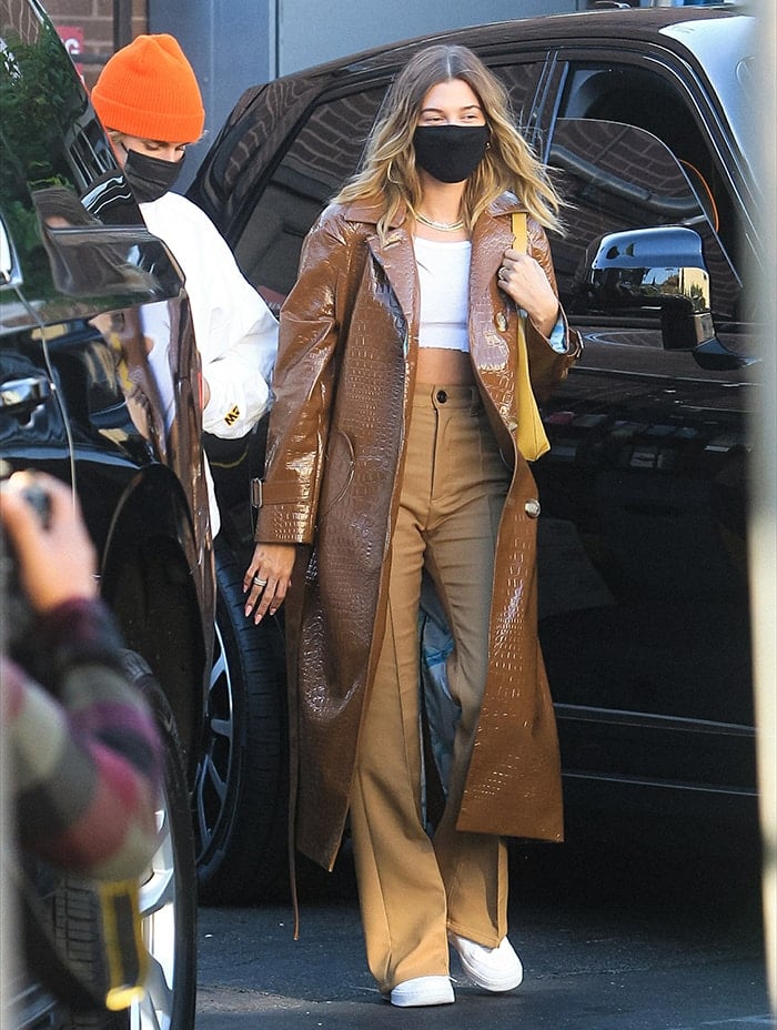 Hailey Bieber wears Meryll Rogge khaki pants with Brandy Melville white tank top and Saks Potts trench coat