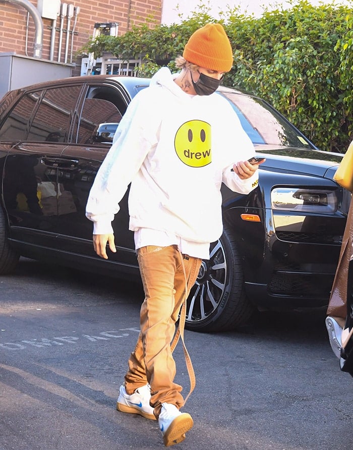 Justin Bieber wears khaki pants with a white hoodie from his Drew House clothing brand