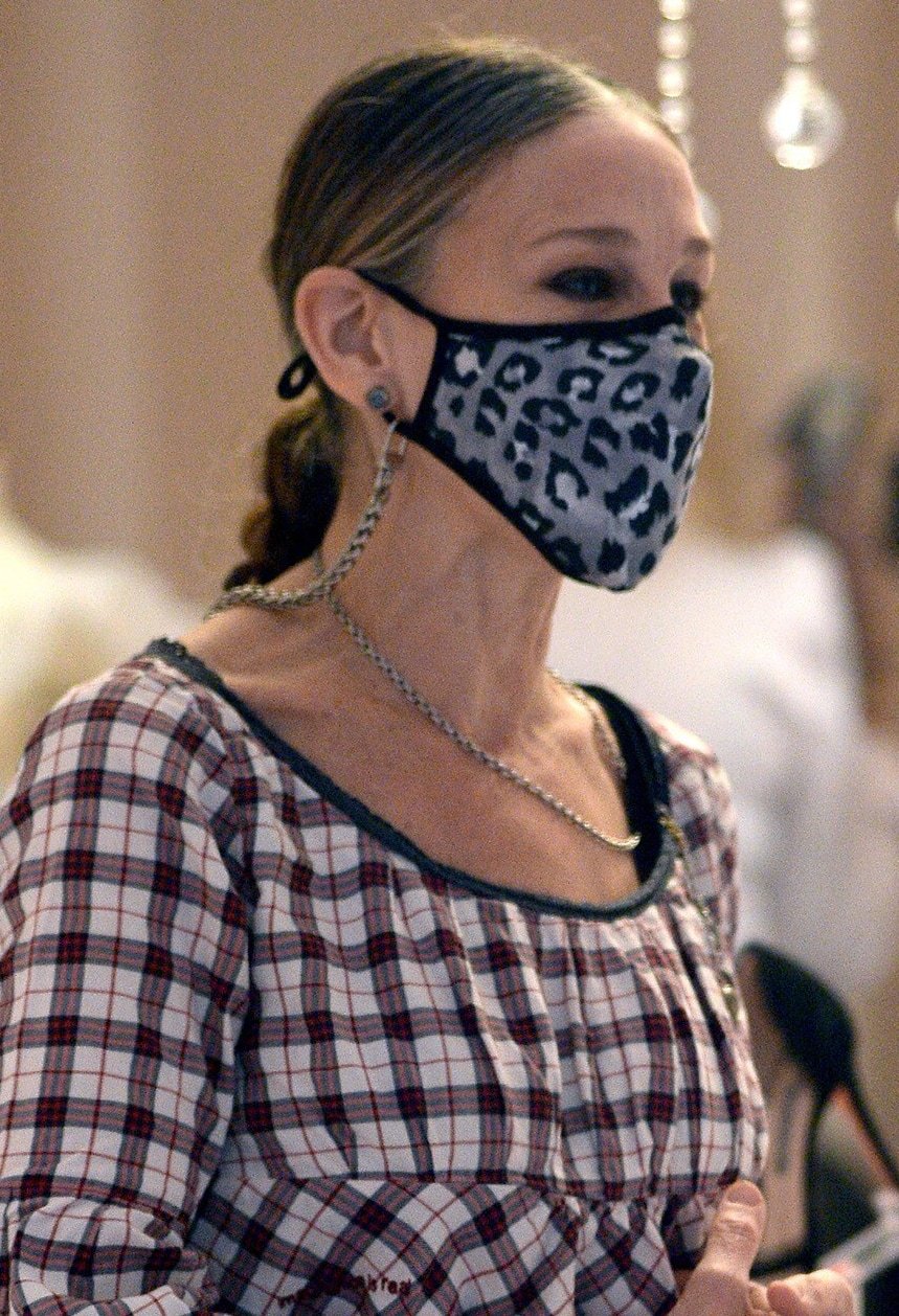 Sarah Jessica Parker styles her hair in a braided ponytail and wears a leopard-print face mask