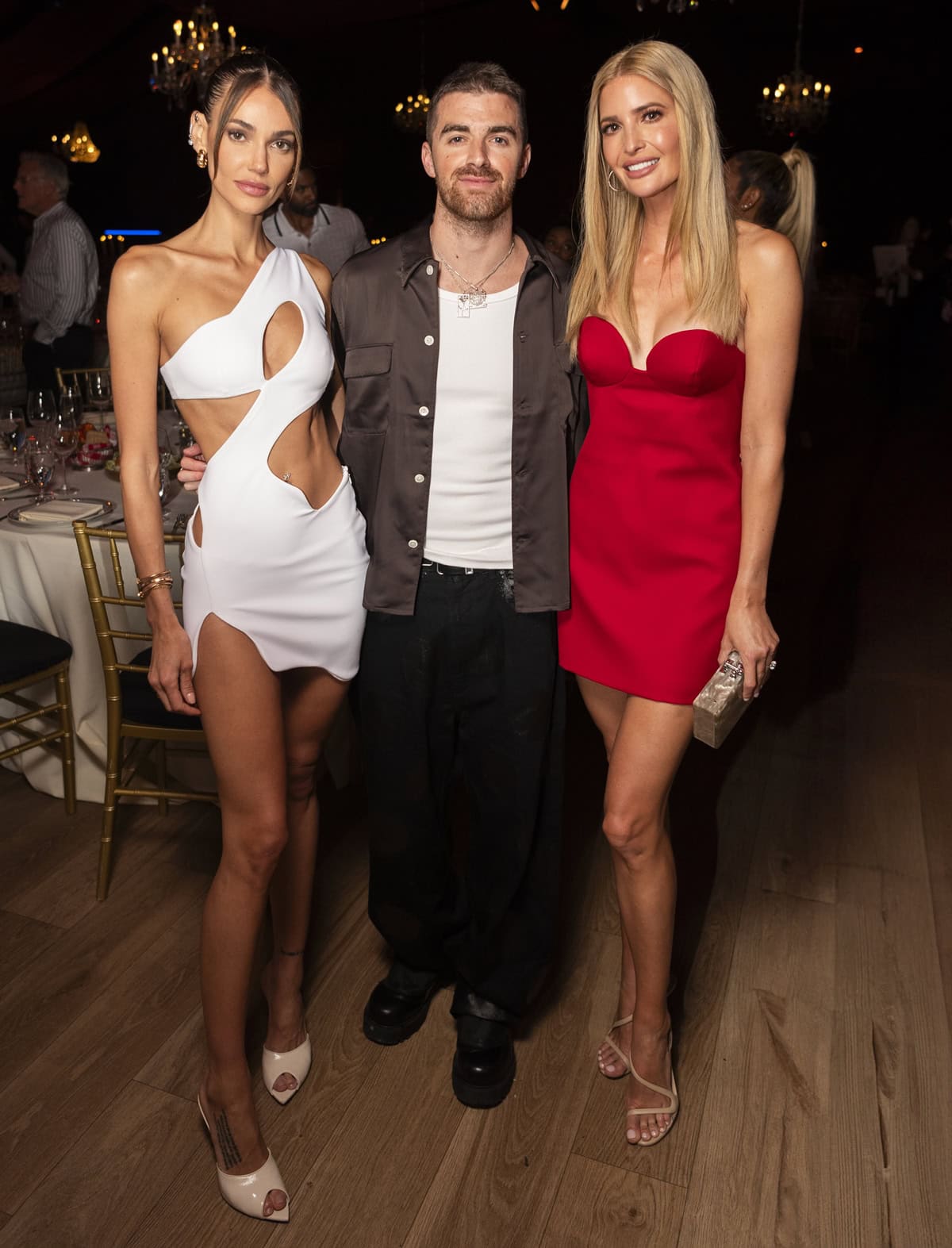 Marianne Fonseca, Andrew "Drew" Taggart, and Ivanka Trump pose together at the Carbone Beach event, with Ivanka stunning in a red Magda Butrym minidress and nude Christian Louboutin Rosalie sandals