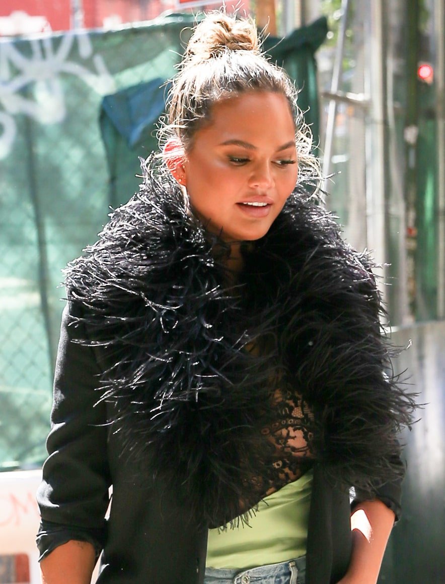 Chrissy Teigen wears a top knot with dewy neutral makeup that highlights her eyes