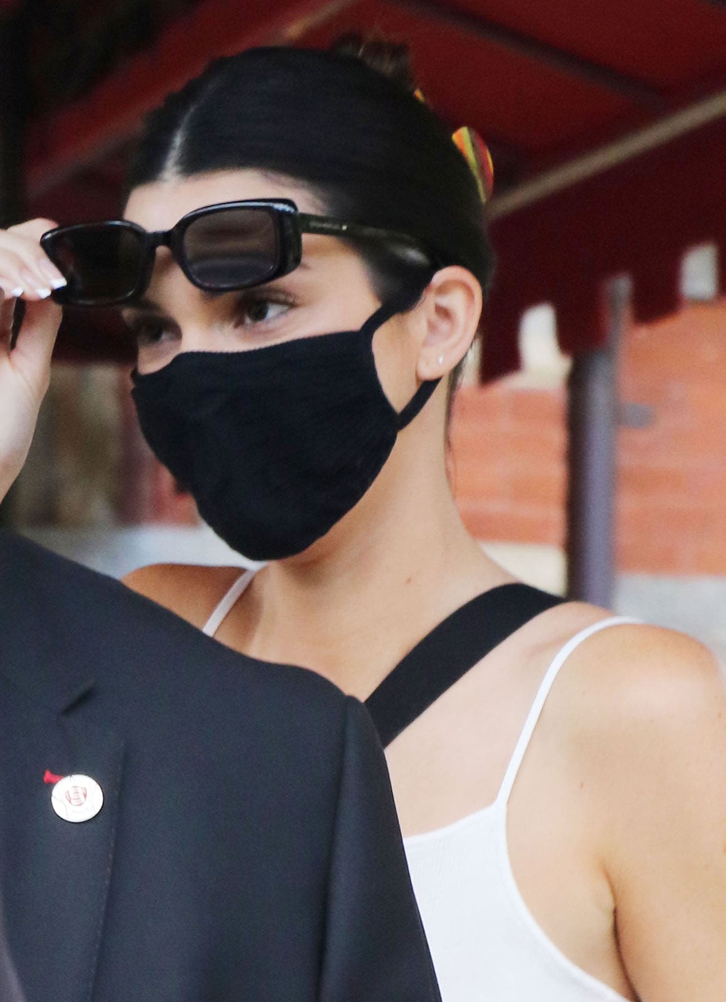 Kendall Jenner wears her tresses up and hides her face behind a face mask and black sunglasses