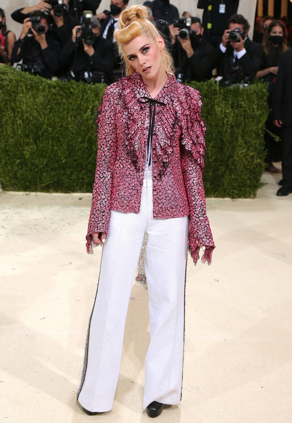 Kristen Stewart looks stunning in a pink ruffled floral blouse and high-waisted wide-leg pants from Chanel's latest collection at the 2021 Met Gala