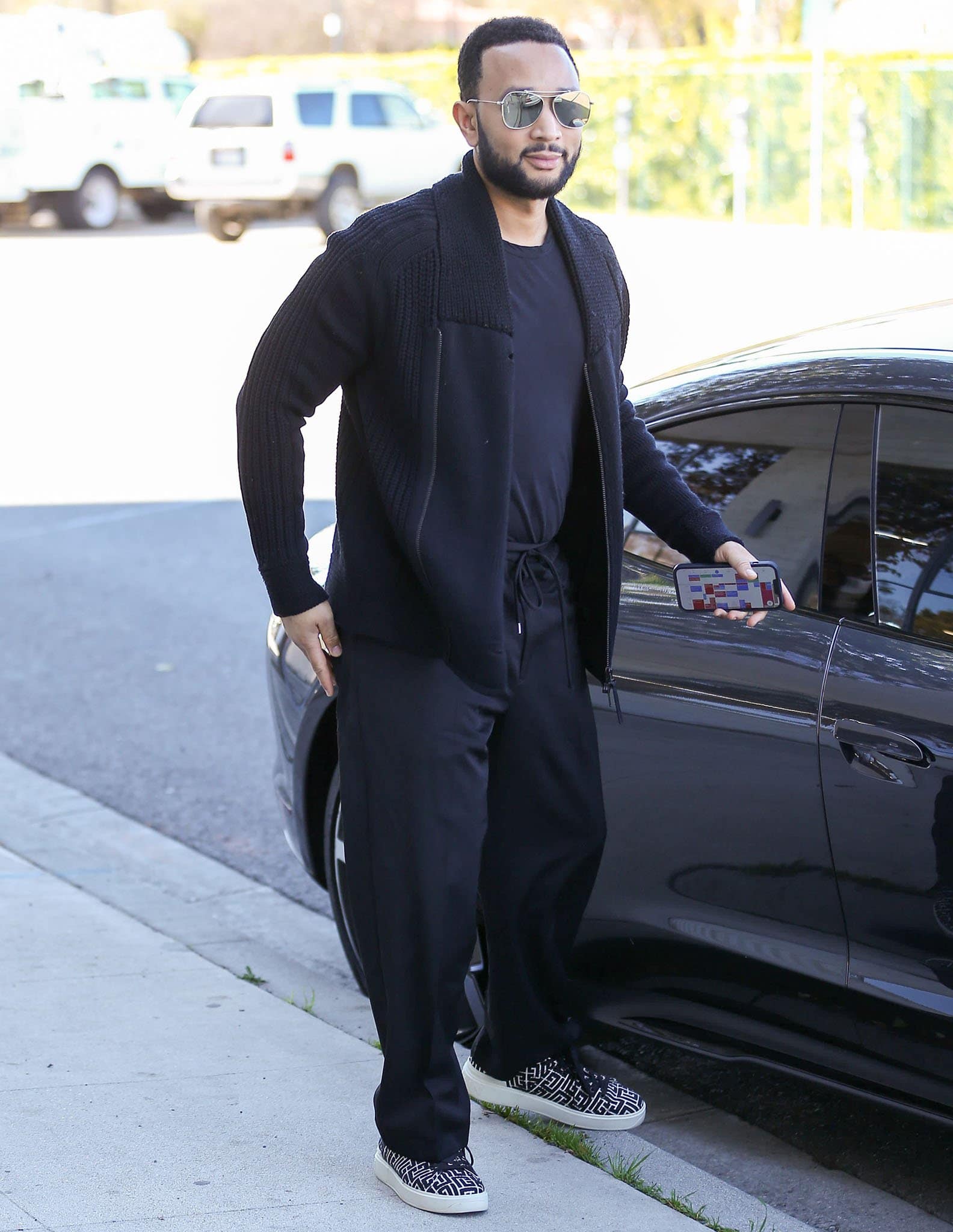 John Legend keeps things cozy in a black tee, cardigan, joggers, and Balmain sneakers