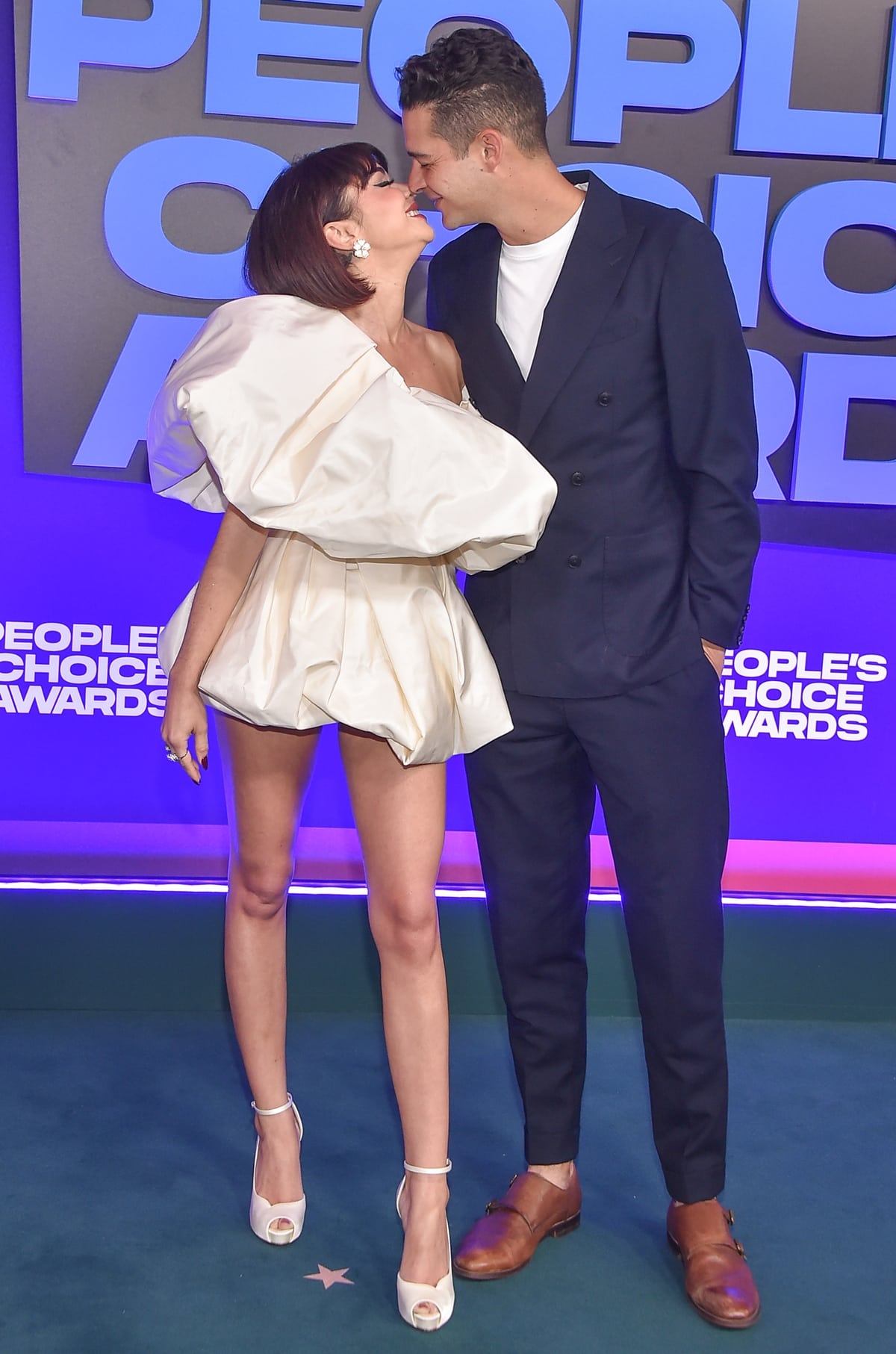 Sarah Hyland in a Vera Wang dress kisses her much taller fiancé Wells Adams at the 2021 E! People’s Choice Awards