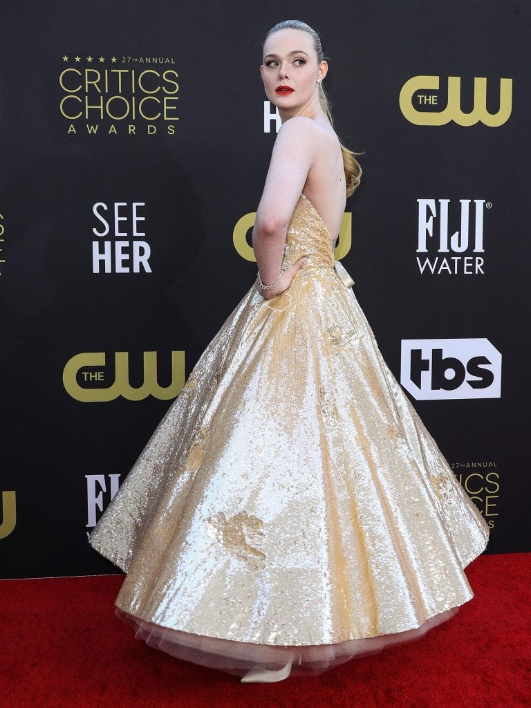 Elle Fanning Poses on Toilet Seat in Gold Ball Gown and Classic White Pumps