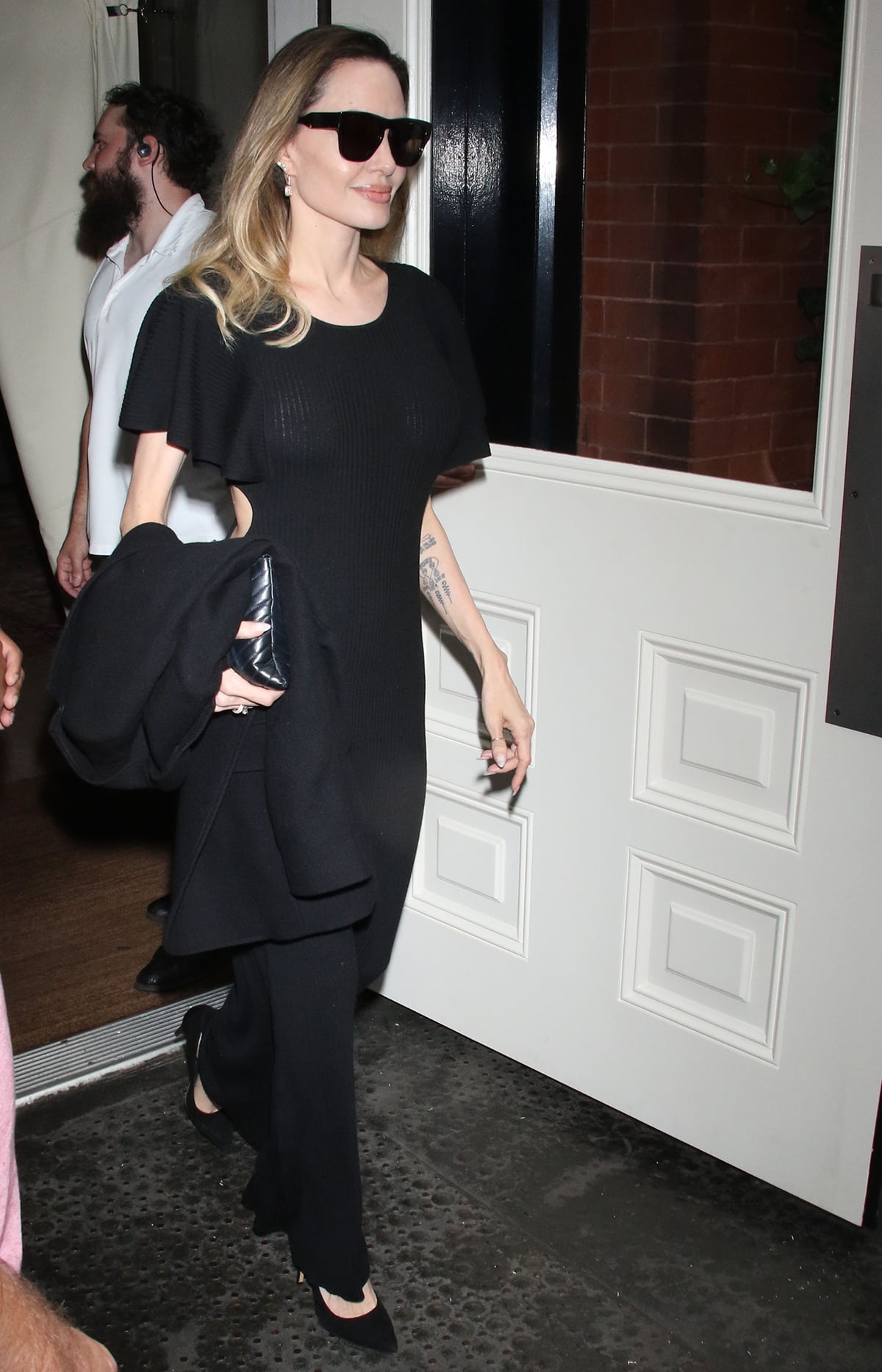 Angelina Jolie shows her take on stealth wealth dressing in a black rib-knit midi dress, black suede pumps, and a black Saint Laurent clutch on August 17, 2023